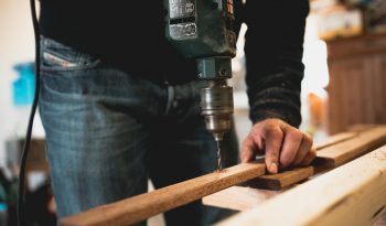 man holding wooden stick while drilling hole