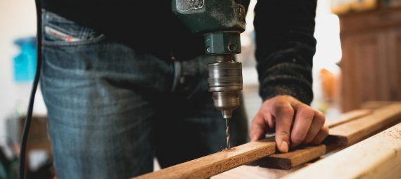 man holding wooden stick while drilling hole